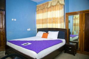Schlafzimmer mit einem Bett mit lila Bettwäsche und einem Spiegel in der Unterkunft Kiverly Guest House in Atasomanso