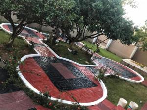 a garden with a red and black rug and trees at Kiverly Guest House in Atasomanso