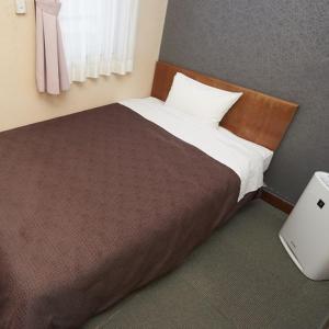 Hotel Select Inn Nishinasuno في ناسوشيوبارا: غرفة نوم مع سرير وبطانية بنية ونافذة
