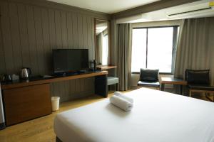 a hotel room with a bed and a flat screen tv at Marine Plaza Hotel Pattaya in Pattaya South