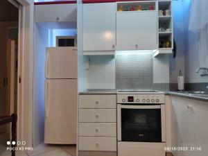 La cuisine est équipée de placards blancs et d'un réfrigérateur blanc. dans l'établissement Smart home,voice activated apartment in kalamata, à Kalamata