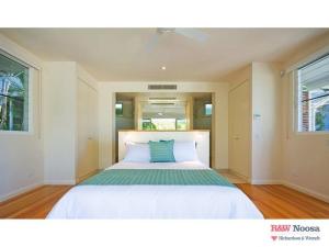 a bedroom with a large white bed with a green pillow at 14 Little Cove Road, Little Cove in Noosa Heads