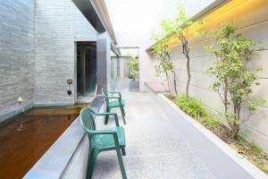two green chairs sitting on the side of a building at Dormy Inn Kanazawa Natural Hot Spring in Kanazawa