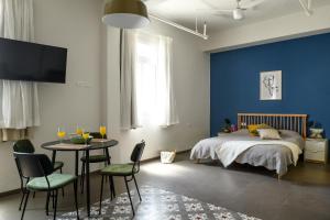 a bedroom with a bed and a table and chairs at The Printhouse - Downtown Boutique Apartments by Sea N' Rent in Haifa