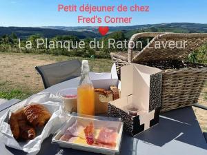 a picnic table with a box of food and a basket of bread at La planque du raton laveur in Lierneux