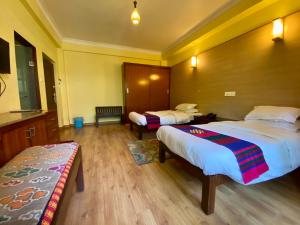 a hotel room with two beds and a bench at Hotel Siddhi Manakamana in Kathmandu