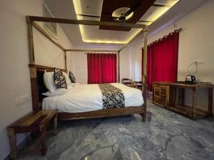 una camera con un grande letto e una tenda rossa di The Aravali Kumbhalgarh a Kumbhalgarh