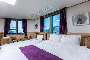 1 Schlafzimmer mit 2 weißen Betten und Fenstern in der Unterkunft Cheonjiyeon Hotel in Seogwipo