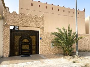 a building with a door with a palm tree in front of it at SHAIKHA villa in Umm al ‘Amad