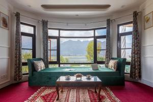 - un salon avec un canapé vert et une grande fenêtre dans l'établissement StayVista at Buhayra Lakefront, à Srinagar