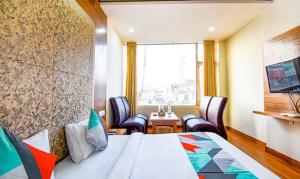 een hotelkamer met een bed en stoelen en een raam bij FabExpress Black Diamond in Zirakpur