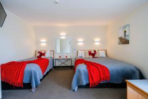 um quarto com duas camas com cobertores vermelhos e azuis em Fiordland Lakeview Motel and Apartments em Te Anau