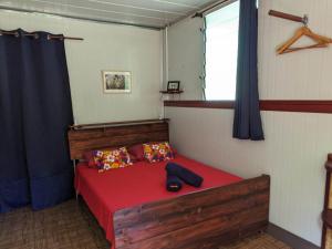 a bedroom with a red bed and a window at Noho Mai in Nuku Hiva