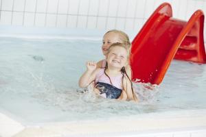 two children playing on a slide in a swimming pool at Storefjell Resort in Gol