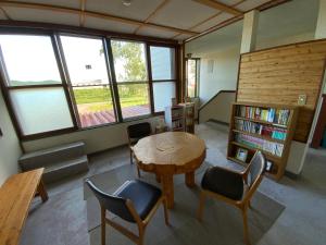 a room with a table and chairs and a book shelf at Mashuko Youth Hostel in Teshikaga