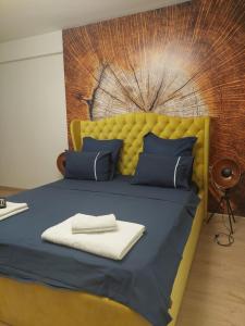 uma cama com uma cabeceira amarela e lençóis e almofadas azuis em Sandanski Apartments Top Center em Sandanski