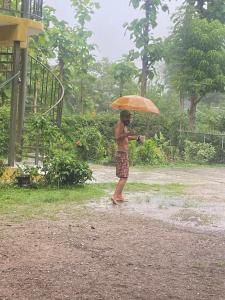 a man standing in the rain holding an umbrella at JJ&J Garden in Pai
