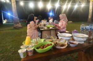 a group of people standing around a table with food at JN Cottage dan Camping Ground in Karimunjawa