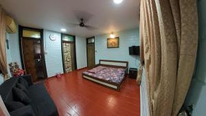 a bedroom with a bed and a couch in a room at UDUPI HOMESTAY - Cottage House - Dendoorkatte in Udupi