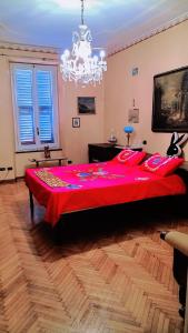 ein großes rotes Bett in einem Schlafzimmer mit einem Kronleuchter in der Unterkunft Nevina centro camera privata in appartamento in Parma