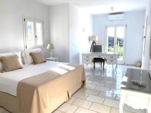 a white bedroom with a bed and a desk at Villa Artemis in Agios Georgios +35 photos