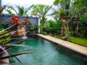 una piscina en un jardín con una fuente en AUREIRIN GUESTHOUSE, en Banyuwangi