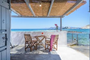una mesa y sillas en un patio con vistas al océano en Esperanza Boathouse, en Mandrakia