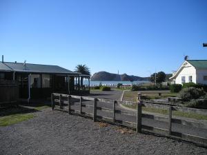 a wooden fence in front of a house and the ocean at Castlepoint Holiday Park & Motels in Castlepoint
