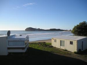 a camper and a trailer on the beach at Castlepoint Holiday Park & Motels in Castlepoint