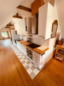uma cozinha com armários brancos e piso em azulejo em Skogslund, Skåne em Veberöd