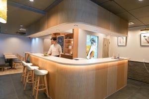 a man standing at a bar in a restaurant at Petit Grande Miyabi in Tokyo