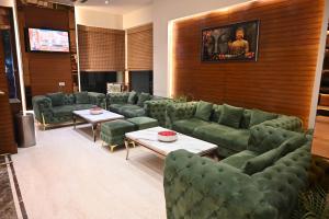 a waiting room with green couches and tables at Deventure Hotel, Karnal in Karnal