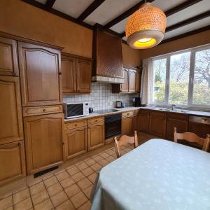 a kitchen with wooden cabinets and a table and a window at On our way to Antwerp, first stop in Mortsel