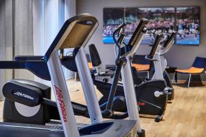 a gym with several tread machines in a room at Holiday Inn Düsseldorf City – Toulouser Allee, an IHG Hotel in Düsseldorf