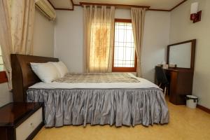 a bedroom with a bed with a dresser and a window at Jisakke Poongyeong Jeju in Seogwipo