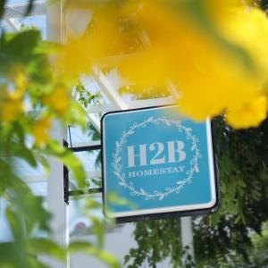 a sign for a hba homesteadership with yellow flowers at Mountains view homestay H2B in Cam Lâm