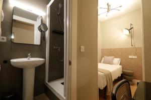 baño pequeño con lavabo y cama en Suites You Gran Vía, en Madrid