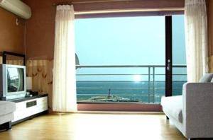 un soggiorno con una grande finestra e una TV di Jisakke Poongyeong Jeju a Seogwipo