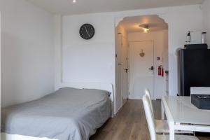 1 dormitorio con cama, mesa y reloj en Sunny Studio - Only 5-Min Walk to Sea & Dunes, en Wijk aan Zee