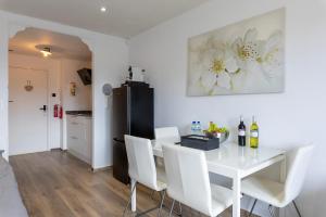 une salle à manger avec une table blanche et des chaises blanches dans l'établissement Sunny Studio - Only 5-Min Walk to Sea & Dunes, à Wijk aan Zee