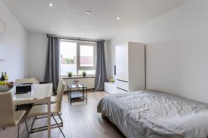 a bedroom with a bed and a desk with a computer at Sunny Studio - Only 5-Min Walk to Sea & Dunes in Wijk aan Zee