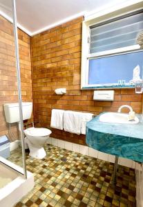 ein Bad mit einem WC, einem Waschbecken und einem Fenster in der Unterkunft Motel Myall in Dalby