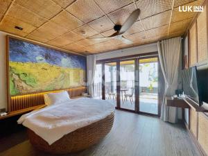a bedroom with a large bed with a large painting on the wall at LUK Inn Hotel - An Thượng, Đà Nẵng in Da Nang
