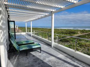 a balcony with a bench and a view of the ocean at Villa Maria in Dwarskersbos
