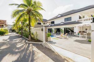 a villa with a palm tree in front of a building at Kamala - 2 BR Pool View Apartment in Kamala Beach