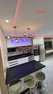 a kitchen with a black counter and stools at Appartement Wow in Al Hoceïma