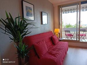een rode bank in een woonkamer met een balkon bij Appartement 2 P 5 PER ENTRE BEAUVAL & CHENONCEAU in Montrichard