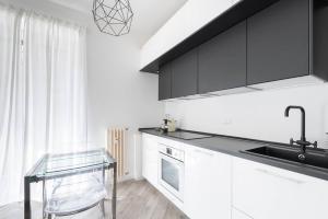 uma cozinha com armários pretos e uma mesa de vidro em Appartamento: BuenosAires79 em Milão