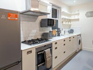 a kitchen with a stove top oven next to a refrigerator at Charming 3BR in Trendy Tottenham Neighborhood in London