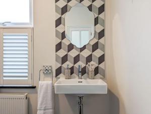 ein Badezimmer mit einem weißen Waschbecken und einem Spiegel in der Unterkunft Charming 3BR in Trendy Tottenham Neighborhood in London